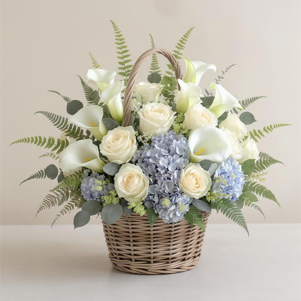 Premium size luxurious flower basket featuring abundant cream roses, white calla lilies, blue hydrangeas, and rich greenery arranged in a wicker basket on a light background — Oceanside florist.