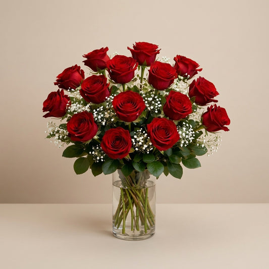 Premium size luxurious long-stem red rose arrangement with abundant roses, rich greenery, and full baby’s breath in a clear round glass vase on a white marble surface — Vista flower delivery.
