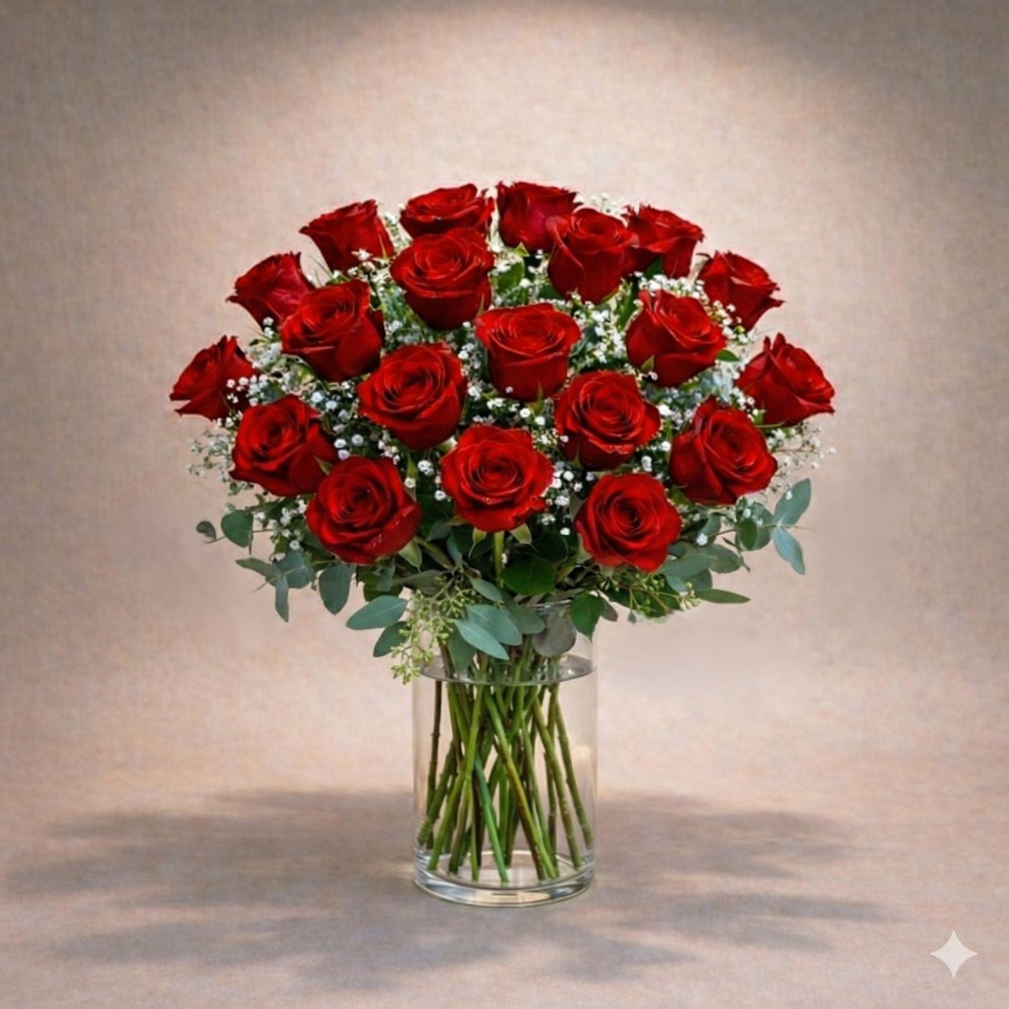 Deluxe size classic red rose arrangement with fuller long-stem red roses, enhanced baby’s breath, and lush greenery in a clear round glass vase — Vista flower delivery.