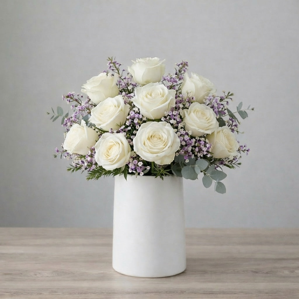 Elegant white rose arrangement with soft lavender waxflower and eucalyptus in a modern matte white vase — Same-day flower delivery Escondido.