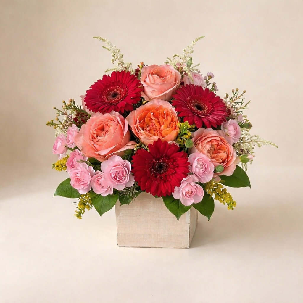 Pink and Red Flower Arrangement featuring blush roses and red gerbera daisies in a garden box.
