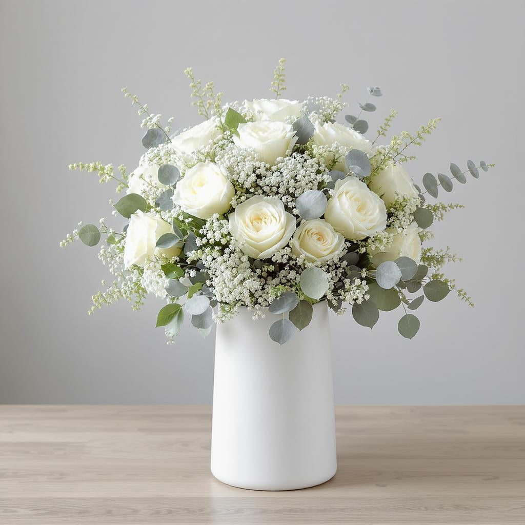 Premium size elegant white rose arrangement with cream roses, baby’s breath, eucalyptus, and lush greenery in a tall white ceramic vase displayed indoors - Escondido flower delivery.