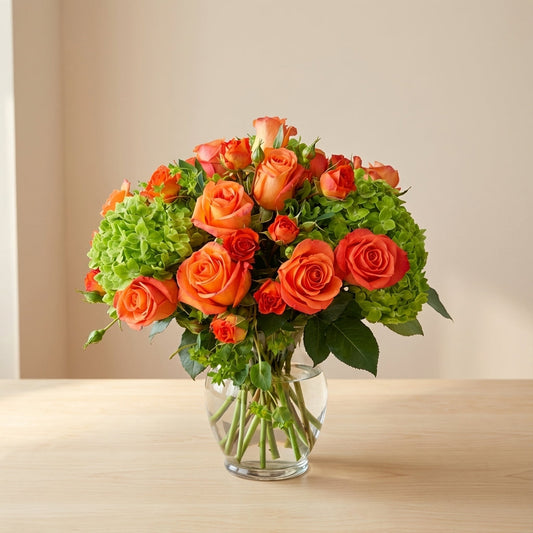 Fresh orange rose and green hydrangea flower arrangement in a glass vase on a wooden table – flower care tips by a local San Marcos florist