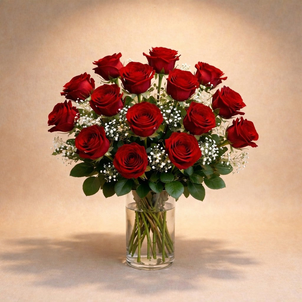Premium size luxurious long-stem red rose arrangement with abundant roses, rich greenery, and full baby’s breath in a clear round glass vase on a white marble surface — Vista flower delivery.