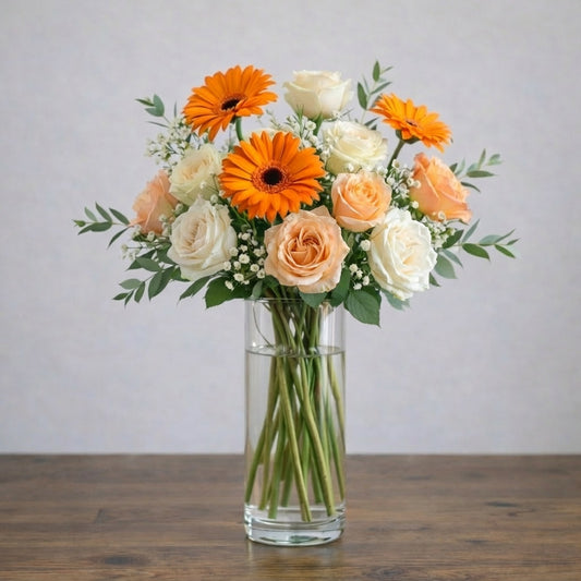 Full size Golden Radiance Bouquet with orange gerberas, cream and apricot roses, and a touch of baby’s breath in a clear glass vase. Local flower delivery to Encinitas.