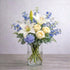 Regular size white lily and cream rose vase arrangement featuring fuller blue hydrangea, layered delphinium, baby’s breath, and lush greenery for a calm, elegant look. Fresh flowers San Marcos CA.