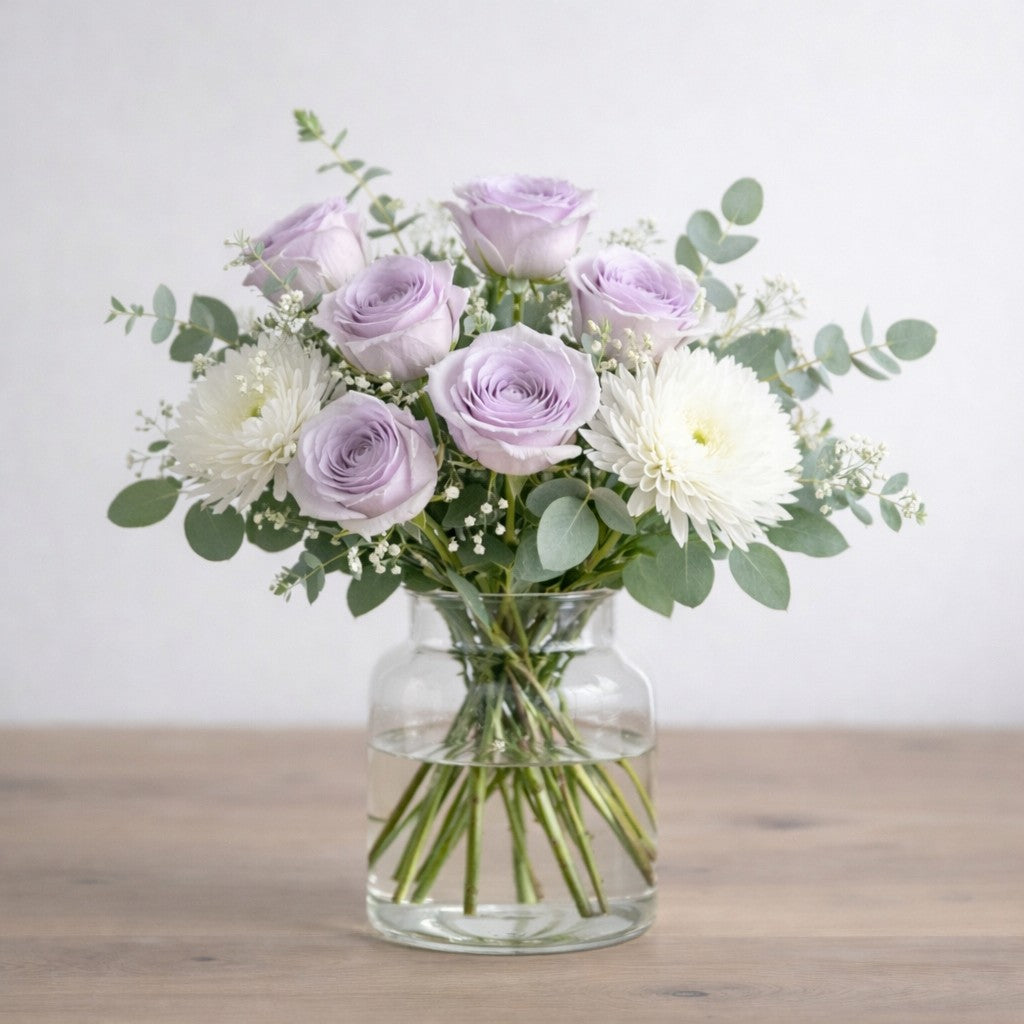 Lavender Grace vase arrangement with soft lavender roses, white chrysanthemums, baby’s breath, and eucalyptus in a clear glass vase - Same-day flowers Carlsbad.