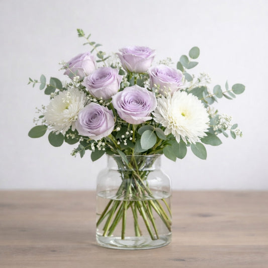 Lavender Grace vase arrangement with soft lavender roses, white chrysanthemums, baby’s breath, and eucalyptus in a clear glass vase - Same-day flowers Carlsbad.