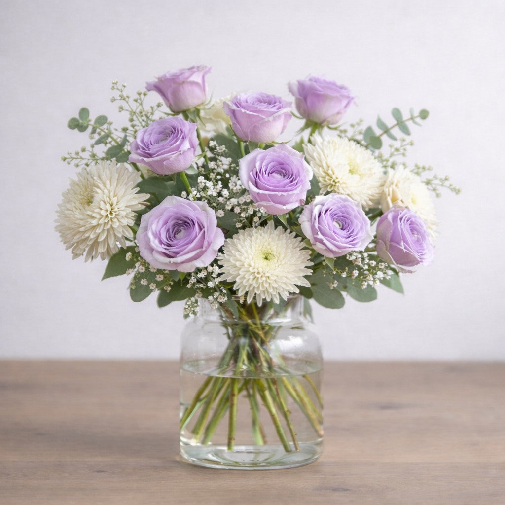 Lavender Grace bouquet featuring lavender roses and white chrysanthemums with airy greenery, arranged naturally in a modern clear glass vase - Same-day flowers Carlsbad.
