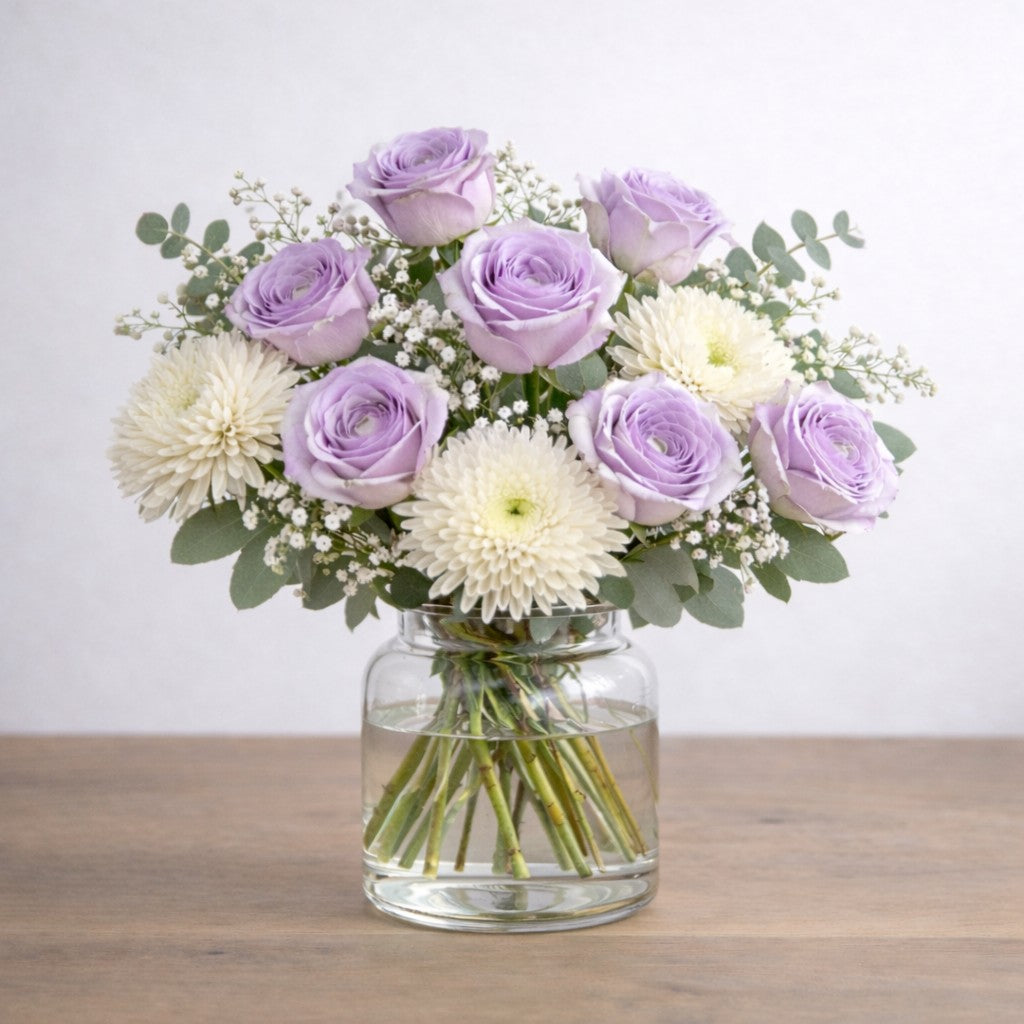 Full size Lavender Grace bouquet featuring lavender roses and white chrysanthemums with airy greenery, arranged naturally in a modern clear glass vase - Same-day flowers Carlsbad.