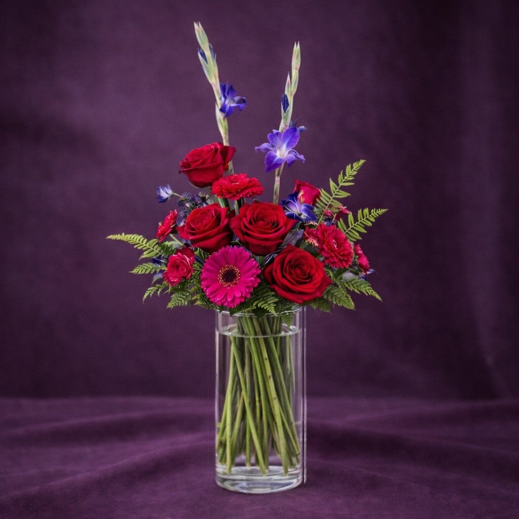 Regular size Romantic Purple & Pink Bouquet featuring fuller red roses, pink gerberas, purple gladiolus, and lush greenery in a vase, Same-day flowers Encinitas.