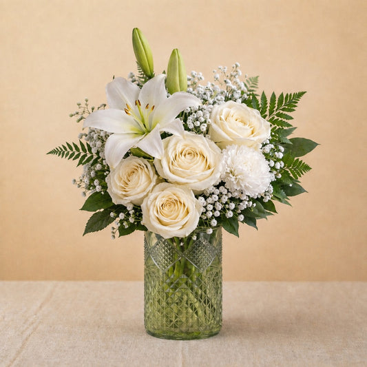 Regular size Serenity Grace white sympathy arrangement featuring white lilies, ivory roses, chrysanthemums, and soft greenery in a clear glass vase — Escondido florist.