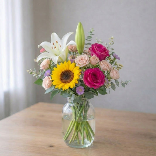 Pink lily, sunflower and rose bouquet in a clear glass vase, cheerful floral arrangement with visible stems, Carlsbad flower delivery