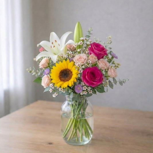 Pink lily, sunflower and rose bouquet in a clear glass vase, cheerful floral arrangement with visible stems, Carlsbad flower delivery