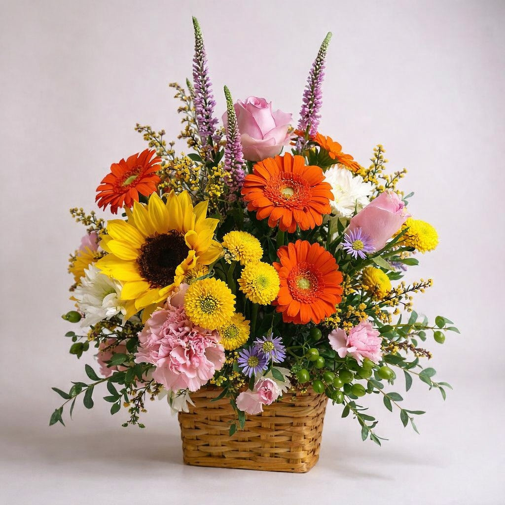 Bright cheerful basket arrangement with sunflowers, orange gerbera daisies, pink roses, white chrysanthemums, and seasonal greenery by a local San Marcos florist.