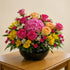 Sunshine Rose Garden Bowl arrangement with pink hydrangea, pink and peach roses, yellow alstroemeria, white daisies, and hot pink button mums in a black ceramic bowl – San Marcos florist delivery