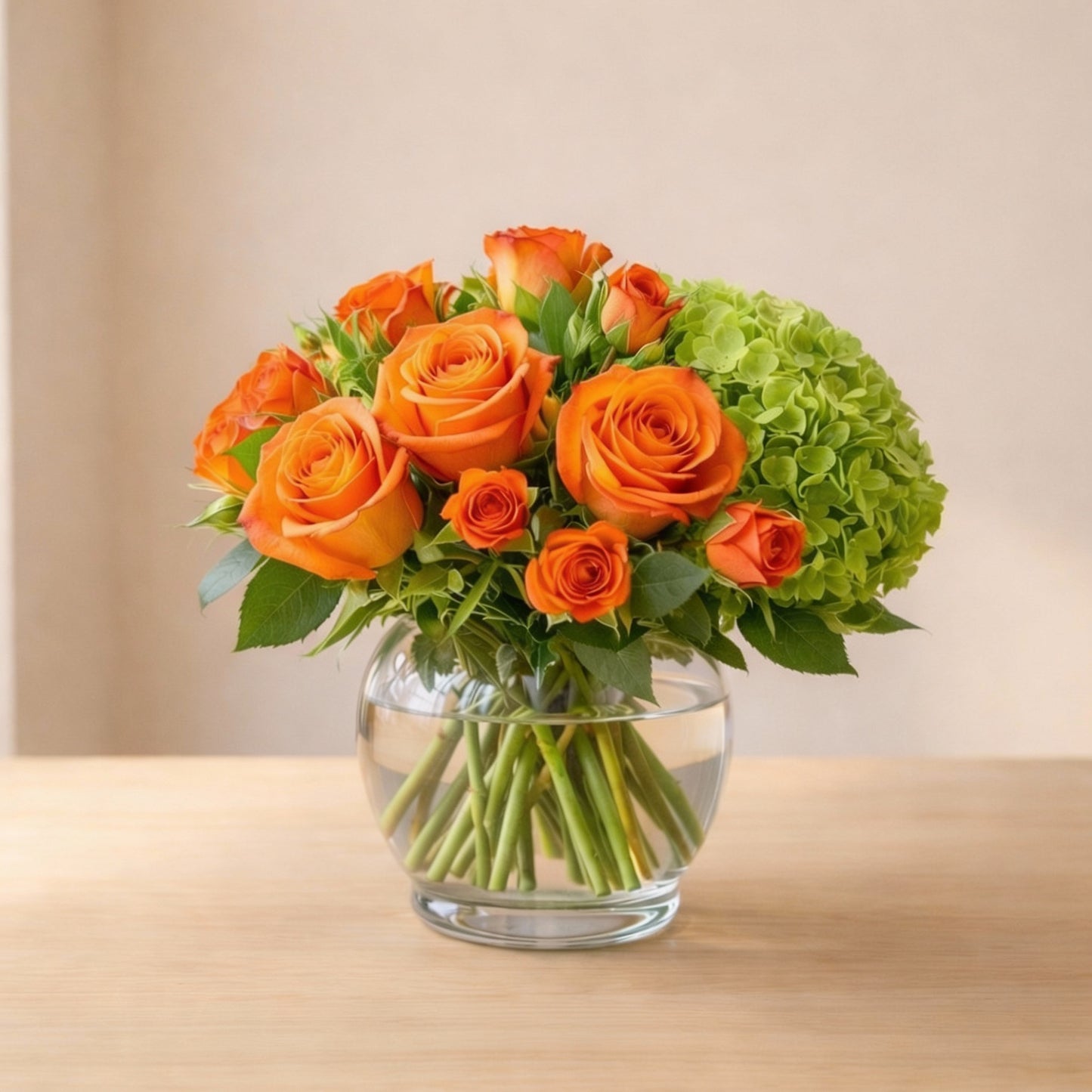 Regular size orange rose and green hydrangea vase arrangement on a light wood table, photographed in soft natural light for a clean product look — fresh flower delivery in San Marcos.