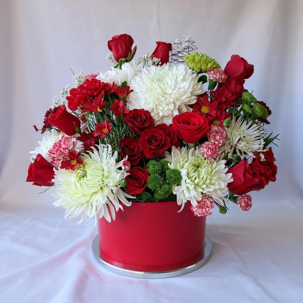 Red and white Christmas floral basket with roses, chrysanthemums and seasonal greenery in a festive red container, handcrafted holiday arrangement - Same-day flowers San Marcos.