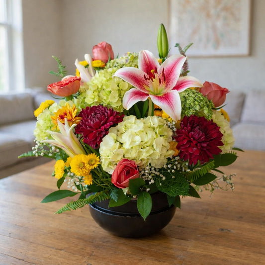 Sunlit Harmony Bowl featuring pink roses, white hydrangeas, lilies, and yellow blooms in a low bowl arrangement, handcrafted flower delivery in Carlsbad.