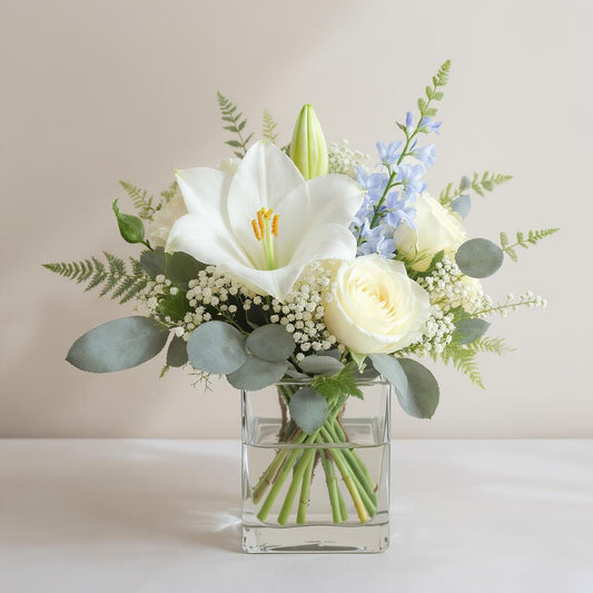 Regular size white and blue fresh flower arrangement with lilies, roses, delphiniums, and eucalyptus in a clear square vase — Fresh flowers San Marcos CA.