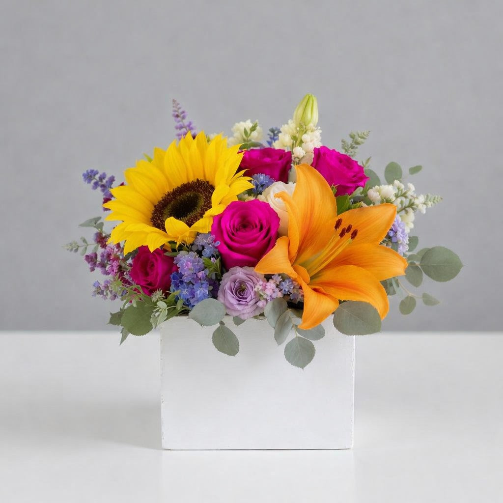 Regular size sunflower and orange lily flower arrangement in white square container with pink roses and seasonal blooms – Carlsbad flower delivery