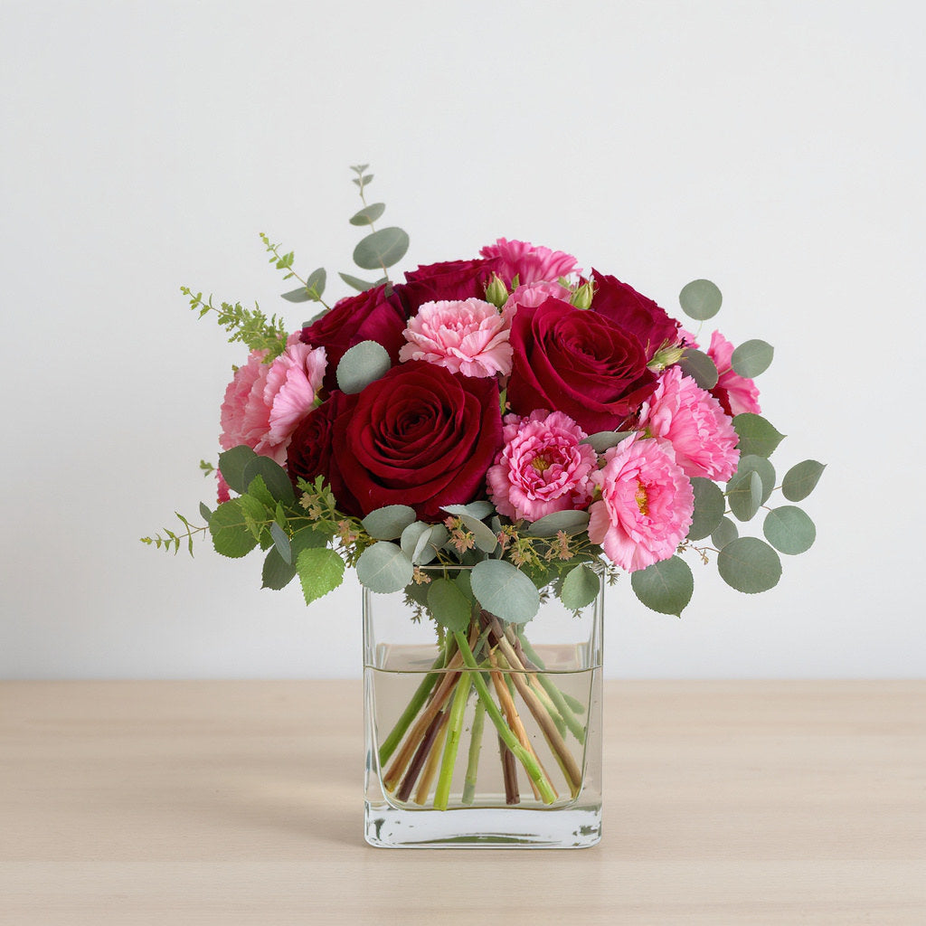 Regular size red and pink fresh flower arrangement with roses, carnations, and greenery in a clear square vase — San Marcos flower delivery.