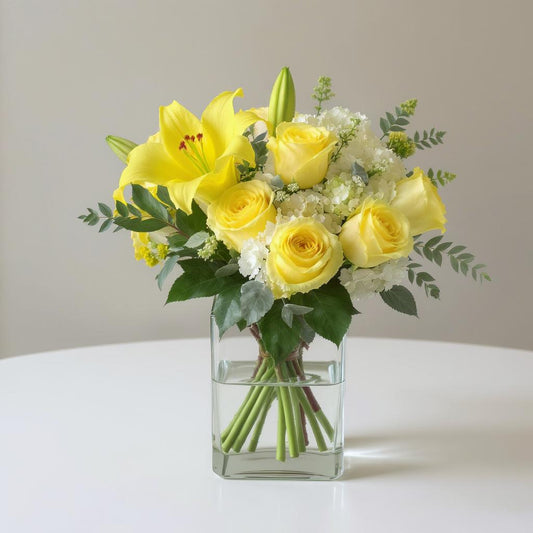 Regular size yellow and white fresh flower arrangement with roses, lilies, and mixed greenery in a clear square vase — Fresh flowers Escondido CA.