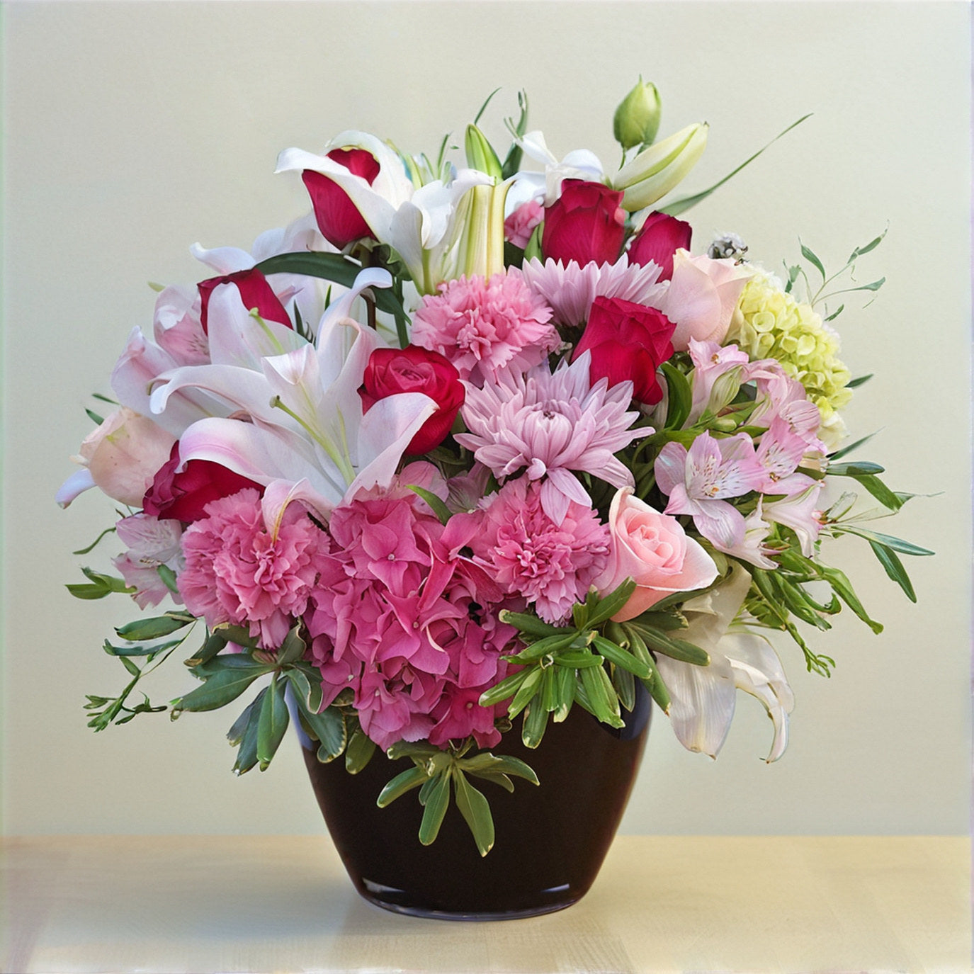 Pink and white fresh flower arrangement featuring lilies, roses, carnations, and assorted greenery in a dark vase — Fresh flowers Oceanside CA.