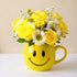 Regular size cheerful yellow bouquet with roses, daisies, and mixed flowers arranged in a yellow smiley mug — fresh flowers Oceanside CA.