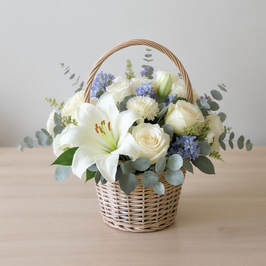 Regular size white and blue floral basket arrangement with lilies, roses, thistles, and eucalyptus in a woven basket — Carlsbad flower delivery.