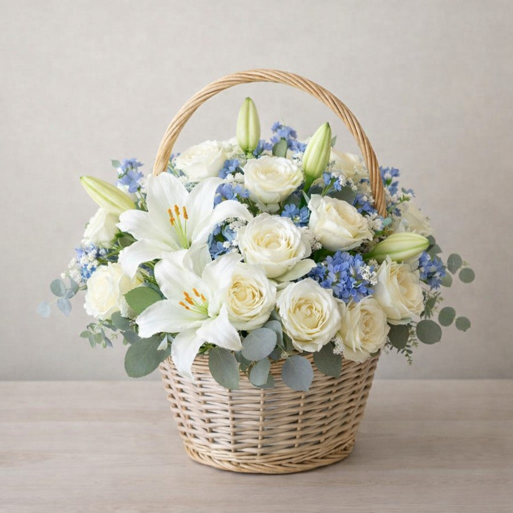 Extra full size white and blue floral basket arrangement with lilies, roses, thistles, and eucalyptus in a woven basket — Carlsbad flower delivery.