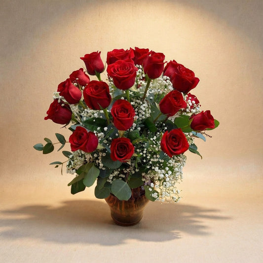 Premium size luxurious long-stem red rose arrangement with abundant roses, rich greenery, and full baby’s breath in a clear round glass vase on a white marble surface — Vista flower delivery.