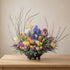 Spring Flower Centerpiece in a modern black bowl with tulips, irises, ranunculus, and pussy willow branches.